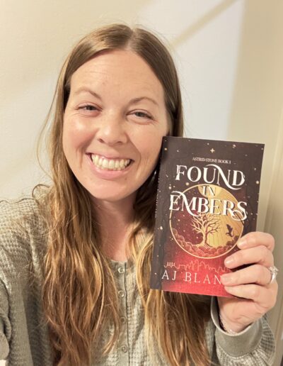 woman holding book, Found in Embers and smiling